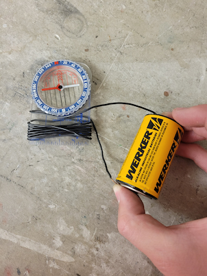 A battery connected to a wire with wrapping around a compass