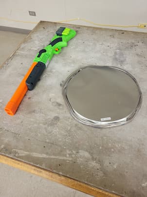 A nerf gun next to a silver pizza pan