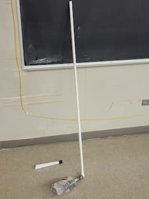 A bottle connected to pvc pipe with a notebook paper rocket next to it