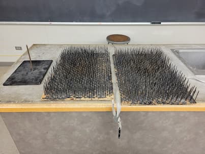 Bed of Nails next to a board with a single nail