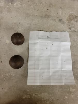 2 rusted steel balls next to a piece of paper
