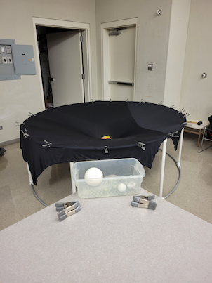 Water filled basketball in the middle of a sheet clipped to a circular pvc pipe stand