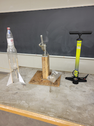 A water rocket next to its launcher and bike pump.