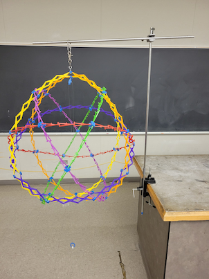 A ball that can expand fully expanded hanging from a rod