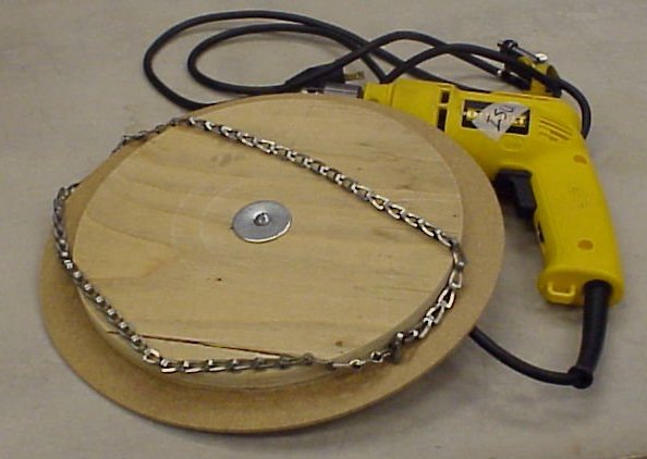 A metal chain with a wooden wheel that inserts into a drill with the drill right next to them.