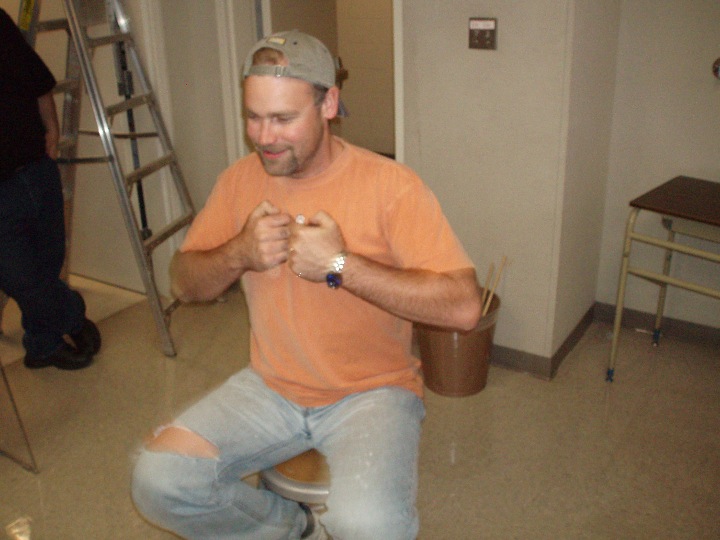 Man sitting on a rotating stool with weights in both hands tucked in