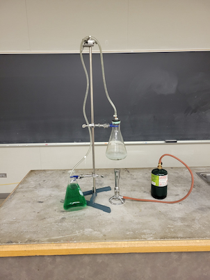 2 flasks connected at different heights with one of the flasks being on top of a bunsen burner