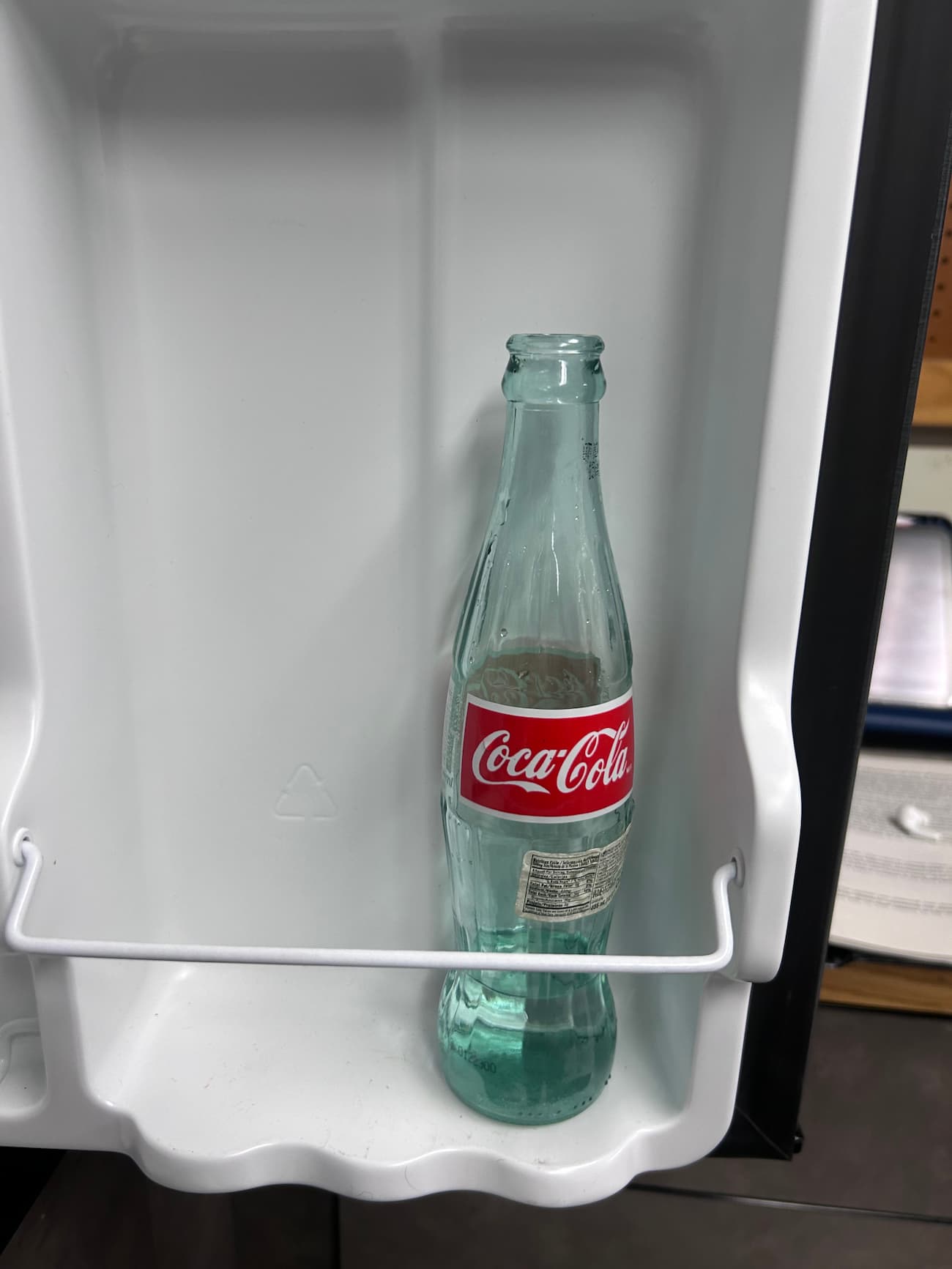 Coke bottle with water sitting in fridge.