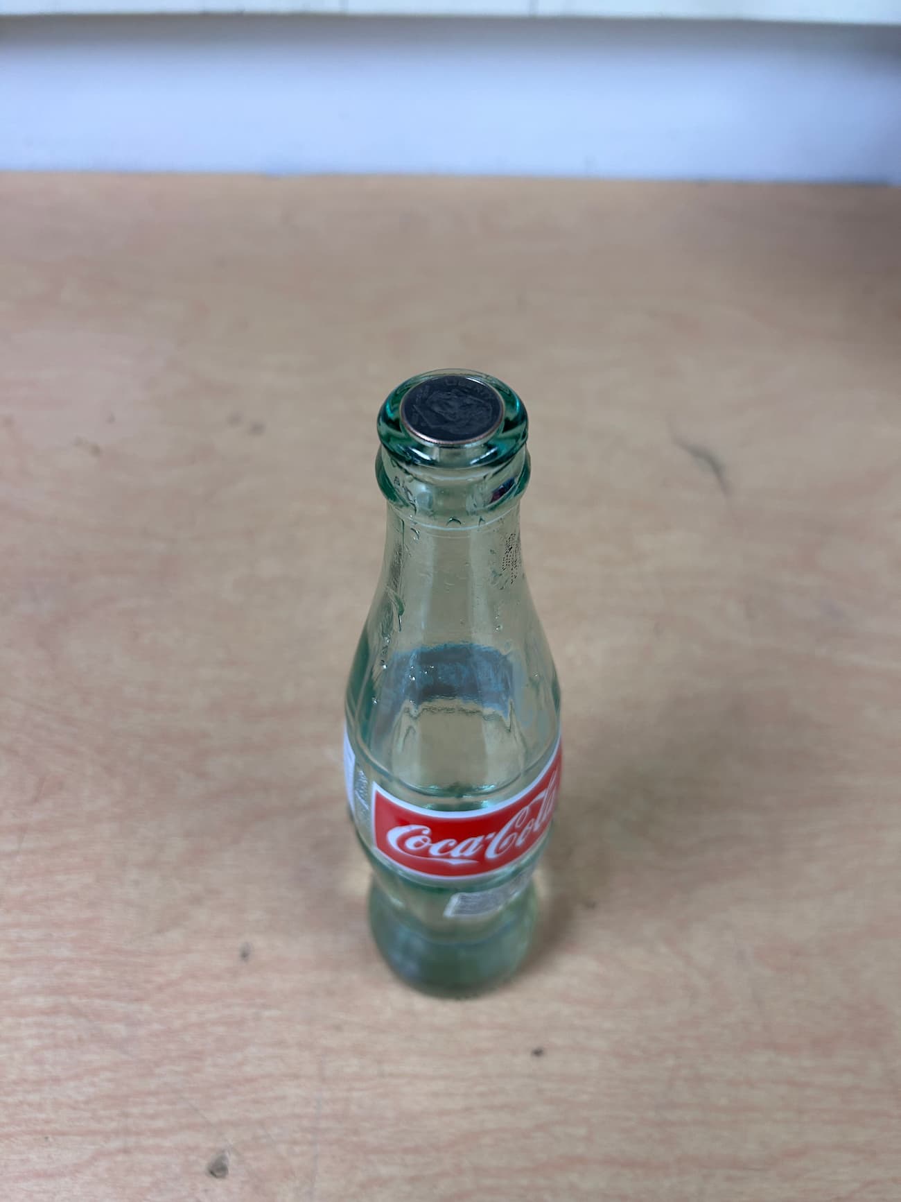 Dime sitting on the opening of a coke bottle.