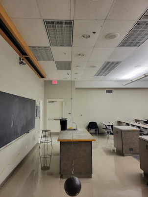 A bowling ball hanging from the ceiling on a flexible metal wire