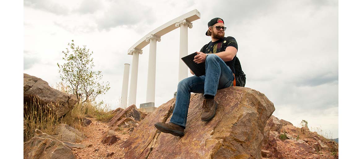 Student sitting outside on a large rock