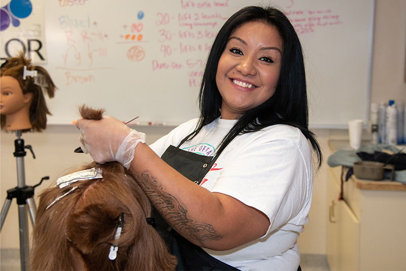 Cosmetology student working on a Library mannequin head