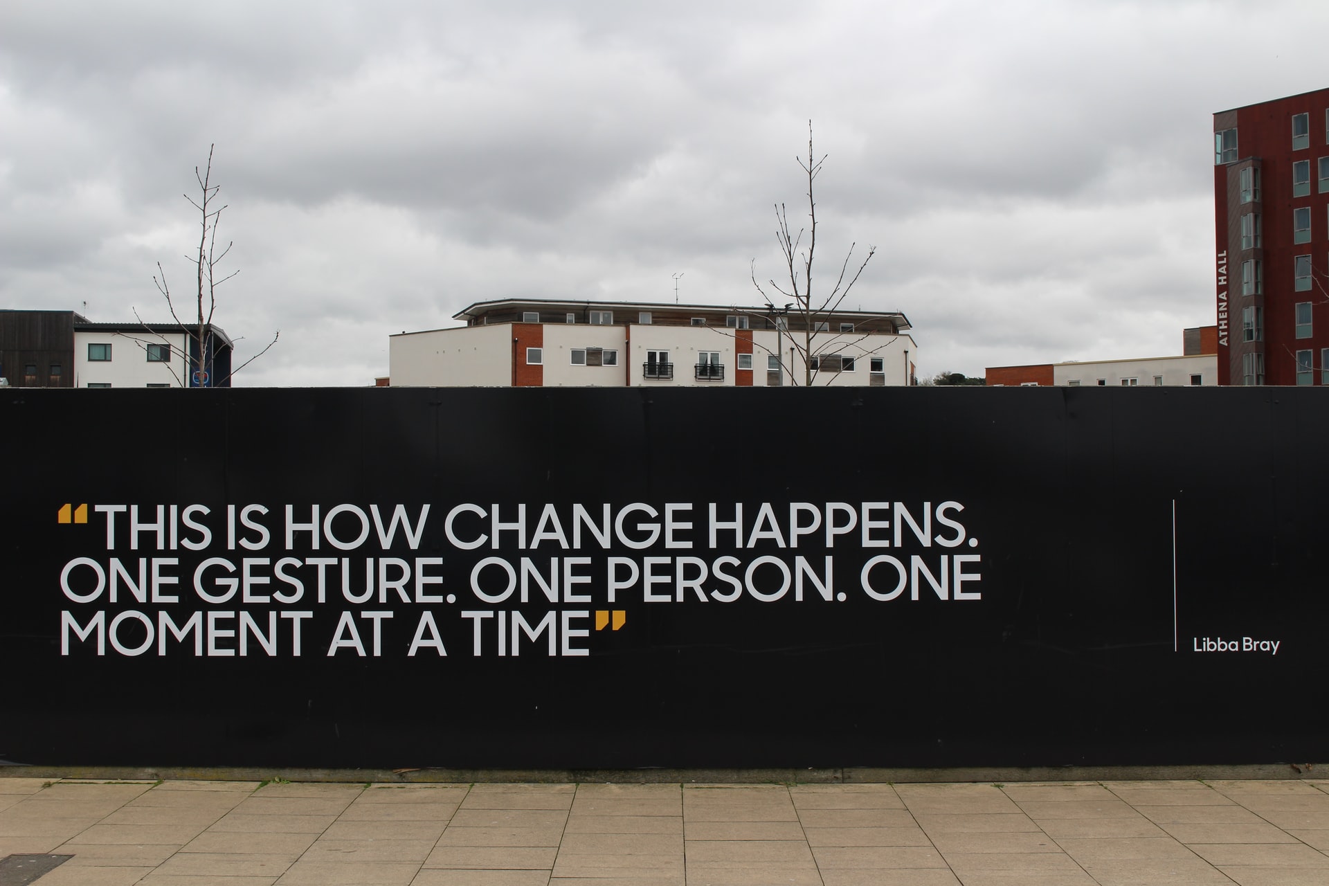 Quote on a black wall in front of buildings: 
