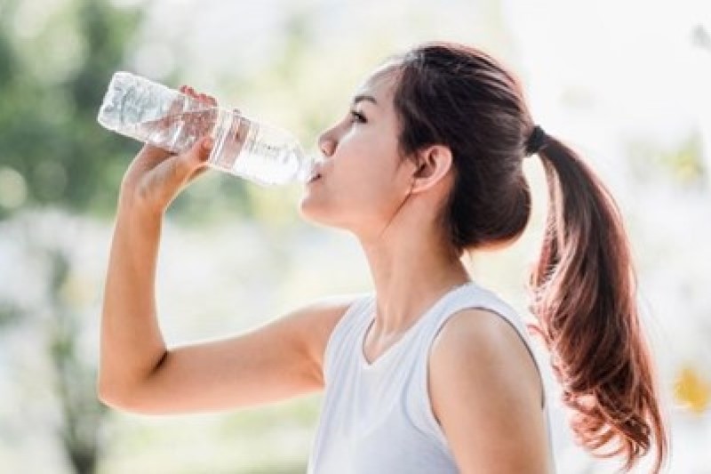 Profile of a woman with a long pony tail drinking a bottle of water