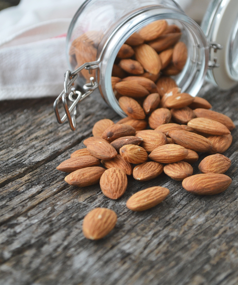 Glass jar tipped over with whole almonds spilling out