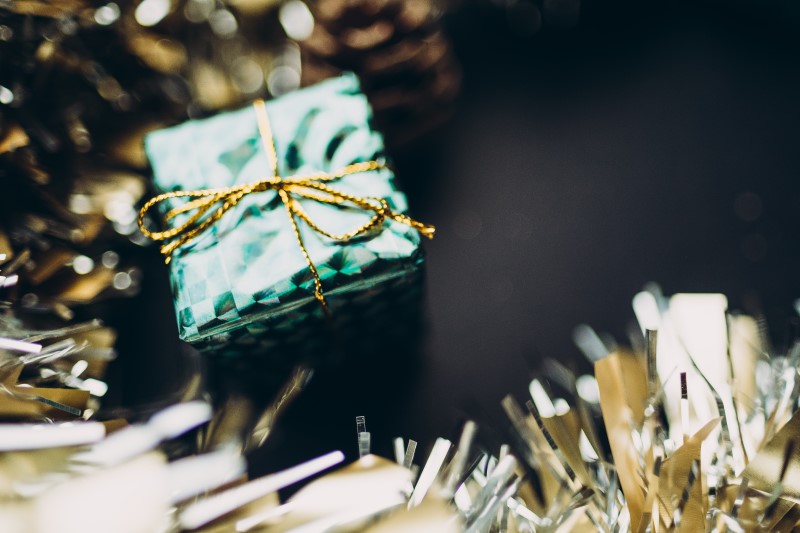 Small present wrapped in green paper with thin gold bow