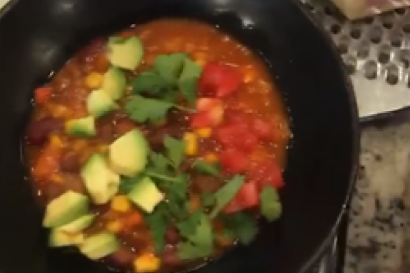 Bowl of lentil soup topped with avocadoes and cilantro
