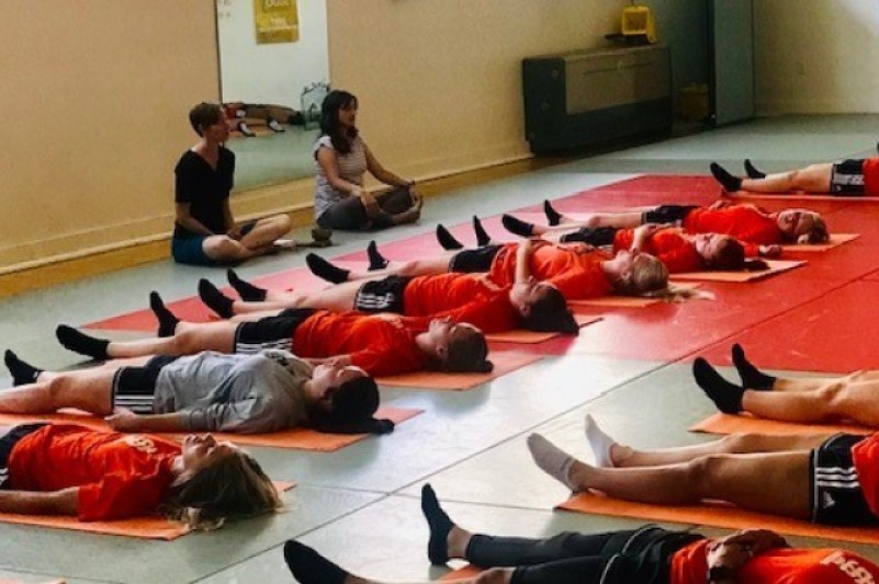 ISU soccer players lie on mats in gym during mindfulness exercise