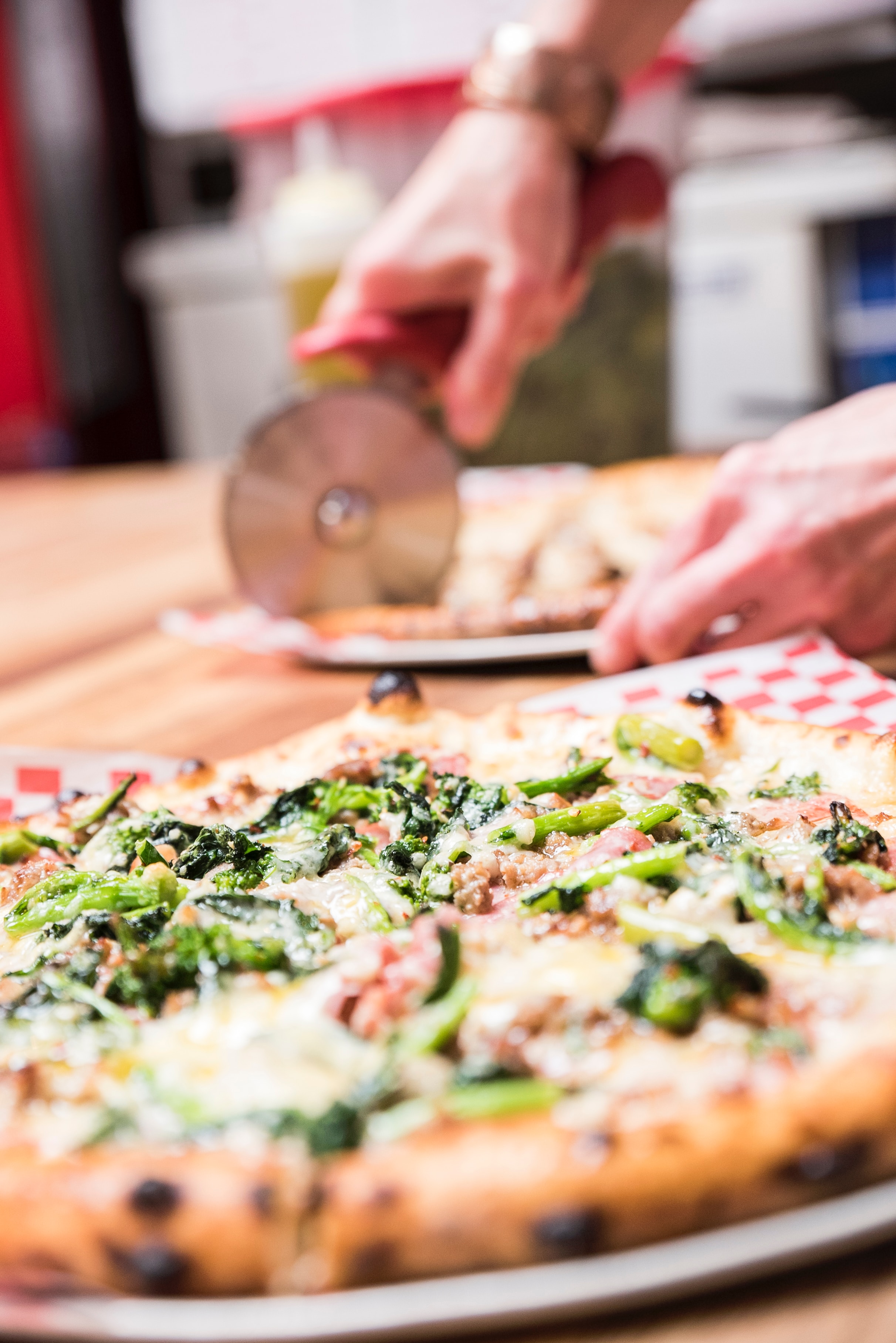 Women slice broccoli pizza