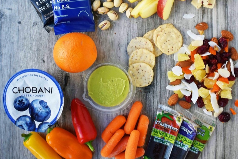 Health snacks, Chobani yogurt, guacamole, veggies, nuts, apple slices, crackers