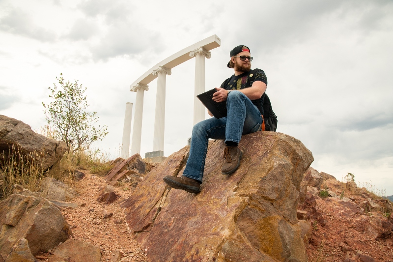 Student sitting on a rock on Red Hill below Pillars.