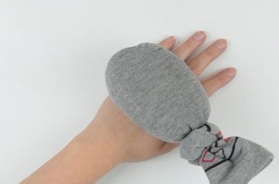 A grey homemade heat pad that looks like a sock with rice in it