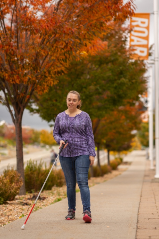 Nicole Hill walks through campus using a white cane.