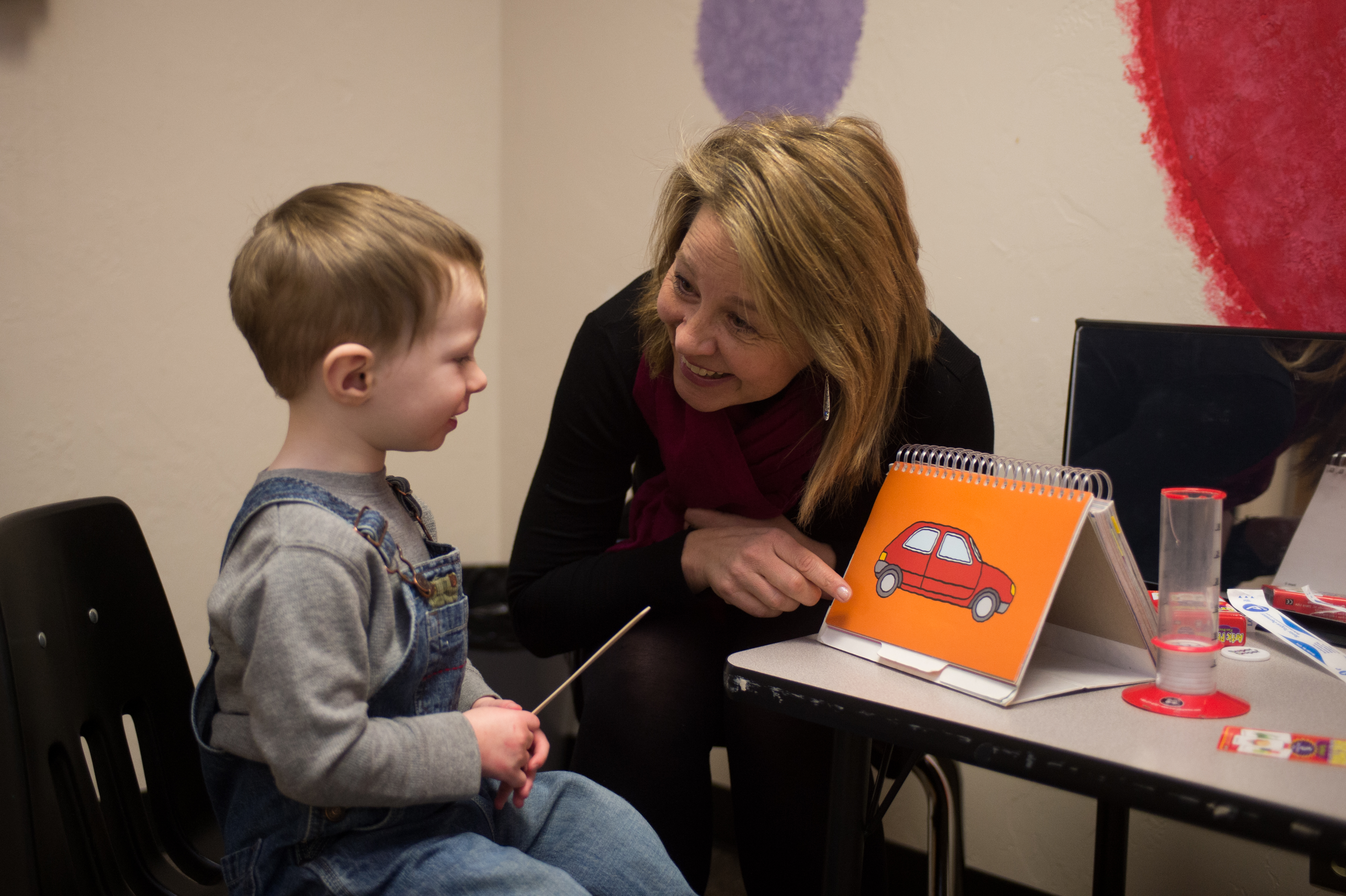 Small child works with a speech language pathologist to recognize an image of a car