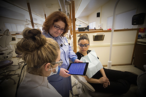 instructor teaches two students in dental hygiene clinic