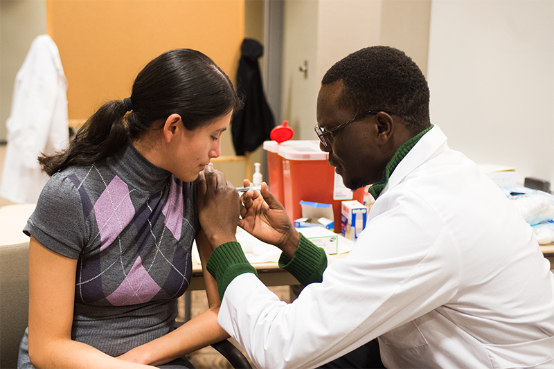 An ISU pharmacy student gives a young woman a vaccine during the Healthy Bengal Wellness Fair