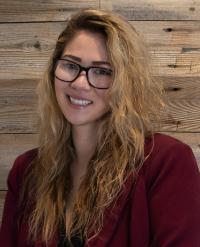 Emma Khang in glasses against a wooden wall