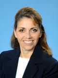 Velma Payne professional headshot with blue background, black jacket, white shirt