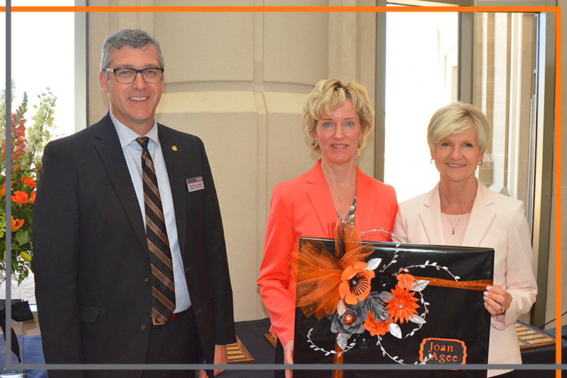 Dr. Rex Force, Karen Neill and Joan Agee pose with a beautifully decorated plaque in the Stephens Performing Arts Center rotunda