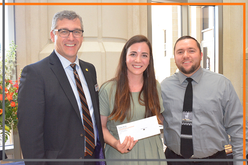 Rex Force presents Kizzy Overdorf with a check in the Stephens Performing Arts Center rotunda