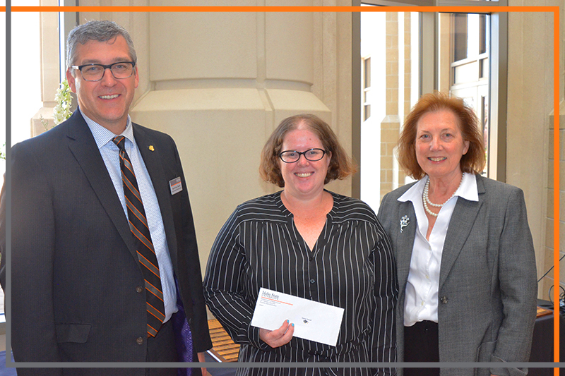 Rex Force presents Tanna Woods with a check in the Stephens Performing Arts Center rotunda
