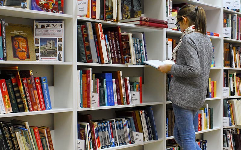 A feminine person browsing in a library
