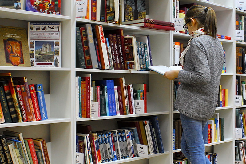 A feminine person browsing in a library