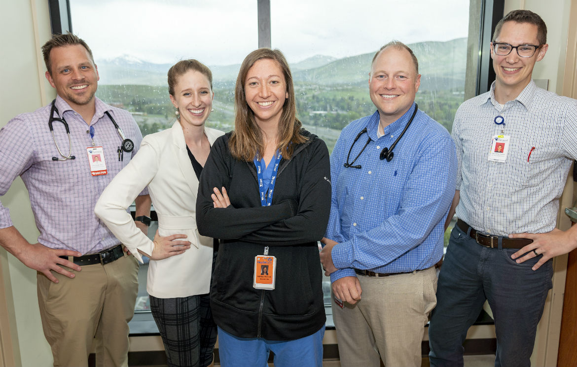 Hospital Medicine Team posing in front of hospital window