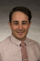 Professional head shot, pink shirt, tan tie