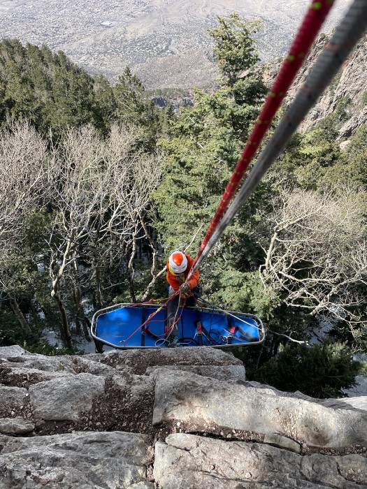 Wilderness team practicing cliffside rescue with blue backboard