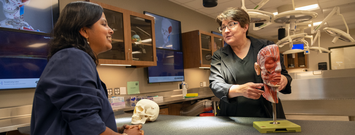 Staff member teaching a student in a biology lab.