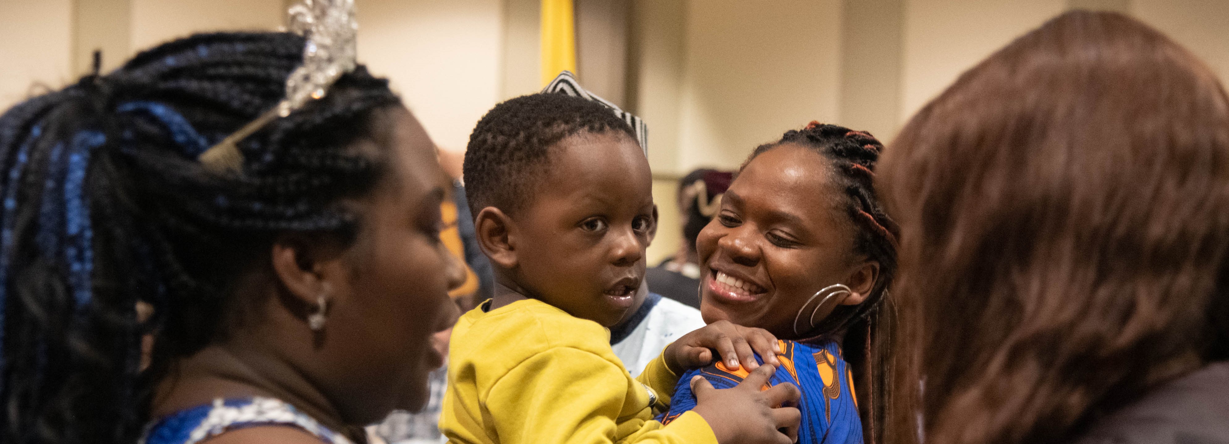 An international student holding her baby and smiling