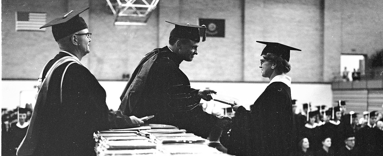 an archived photo from the 60s of a student being handed her diploma