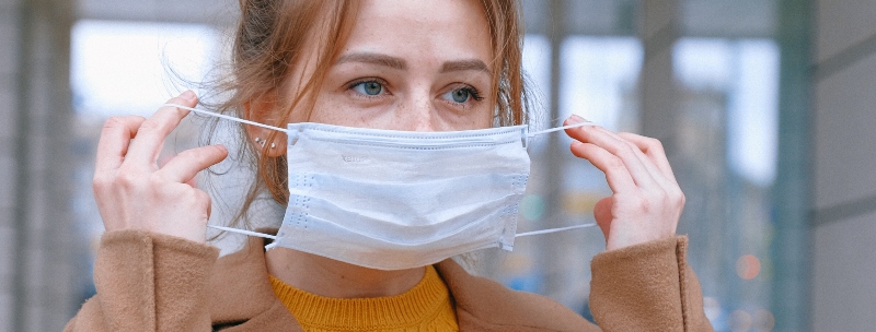 A woman putting on a medical mask