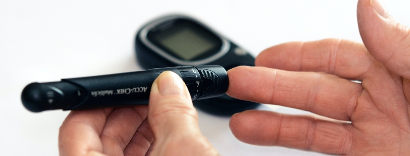 An individual pokes their finger with a blood sugar monitor.