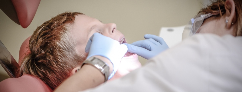 A dental professional checking a boy's teeth
