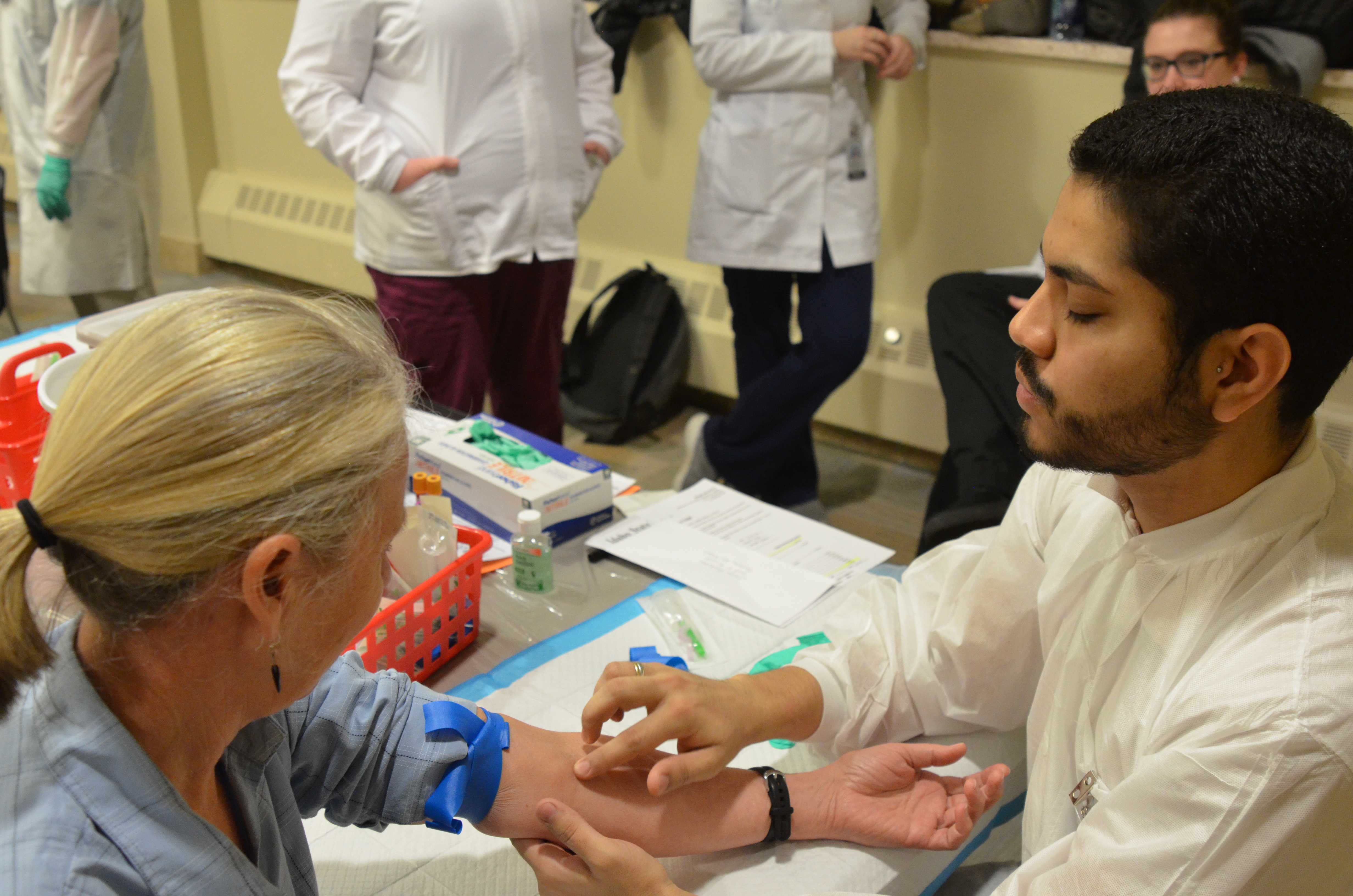 Student lab worker prepares to draw patient's blood at ISU Health Fair 2018