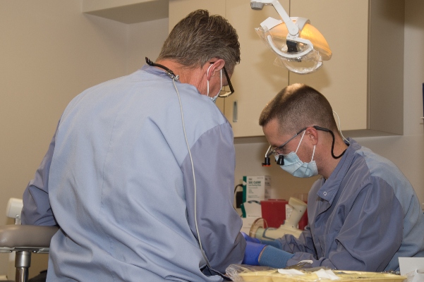 Two dentists in PPE working together over a dentist's chair