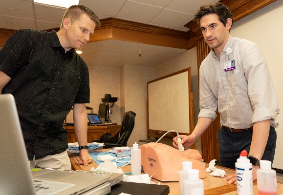 A medical student using ultrasound technology with their supervisor present