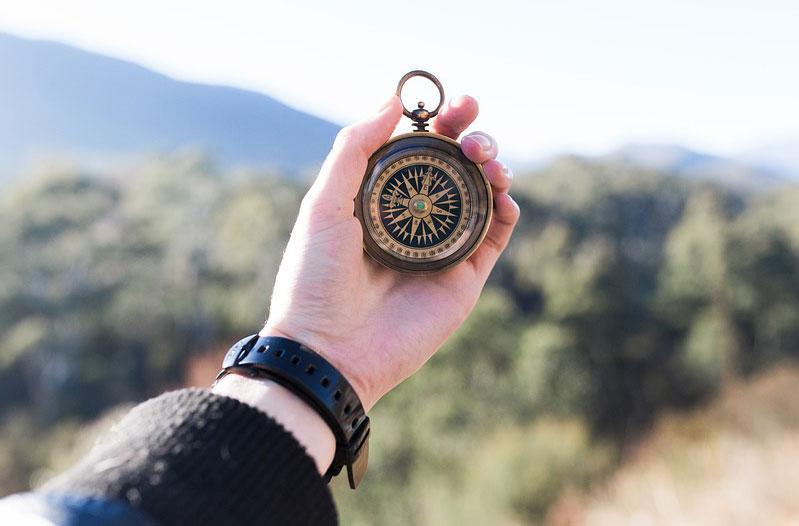 A hand holding a compass.